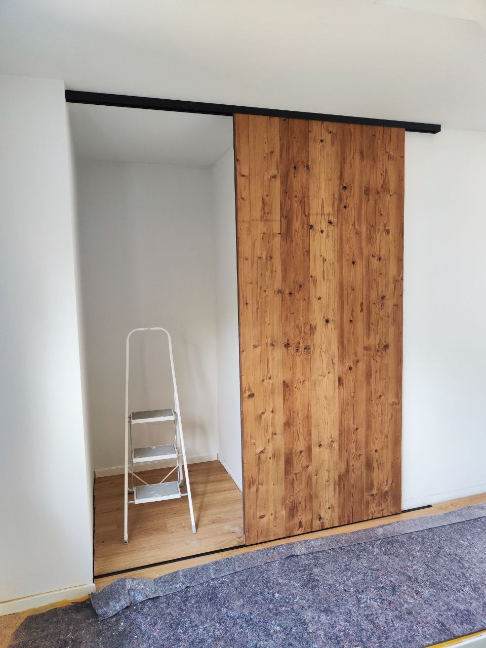 Schiebetür aus Alt-Holz als Verkleidung des Aufzugsschachts